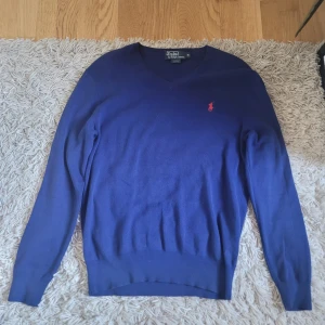 Marinblå v-ringad tröja från Polo Ralph Lauren - Säljer en marinblå v-ringad tröja från Polo Ralph Lauren. Tröjan har lång ärm och är i slim fit-modell. Kan fraktas inom 24h, skriv till mig om ni har frågor. I helt ny skick.