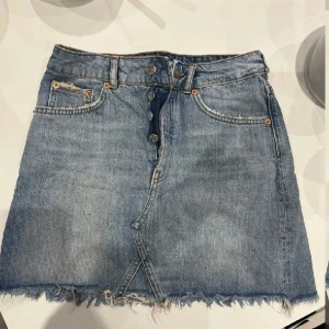 Jeanskjol med knappar framtill - Säljer en klassisk blå jeanskjol med knappar framtill och rå kant nertill. Använd en gång💗