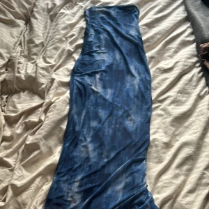 Villig och pruta. Blå långklänning med slits - Snygg blå långklänning med slits baktill. Klänningen har en åtsittande passform upptill och är ärmlös, perfekt för sommarens tillfällen. Materialet känns mjukt och följsamt.