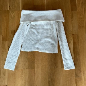 Vit offshoulder stickad tröja från H&M - Säljer en vit stickad offshoulder-tröja från H&M i storlek S. Tröjan har ribbad struktur och långa ärmar, perfekt för att skapa en stilren och trendig look.