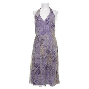 David Meister i siden  - Säljer en lila halterneckklänning från David Meister med paisleymönster i lila, beige och grå toner. Klänningen har omlott-v-ringning och är ärmlös med ett lätt, glansigt foder. Perfekt för sommarens tillfällen!