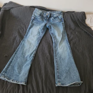 Blå bootcut jeans - Säljer ett par klassiska blå bootcut jeans med normal passform. Jeansen har fem fickor, knapp och dragkedja framtill samt utsvängda ben. Perfekta för dig som gillar en retroinspirerad stil.❣️