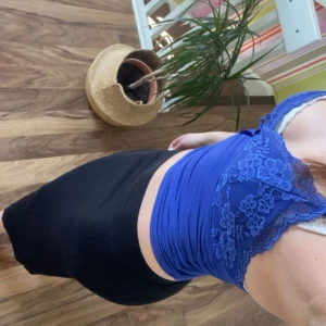 Blå spetslinnetopp med blommönster - Supersöt blå linnetopp med blommig spets upptill och smala axelband. Toppen är figurnära och har en mjuk, stretchig känsla. Perfekt för dig som gillar en feminin och trendig look.