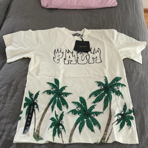 Palm Angels Palm&Skull  - Hej, säljer denna Palm Angels T-shirten i storlek Medium, en perfekt och fet T-shirt till sommaren.  Den är helt ny och taggarna sitter kvar, aldrig använd. Påsen medföljer. Kan gå ner i pris vid snabb handel, fraktar samma dag. 