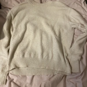 Vit stickad tröja med rund hals - Mysig vit stickad tröja med rund halsringning och ribbade muddar vid ärmslut och nederkant. Perfekt för lager-på-lager och passar till allt. Enkel och stilren design som är lätt att matcha med andra plagg.