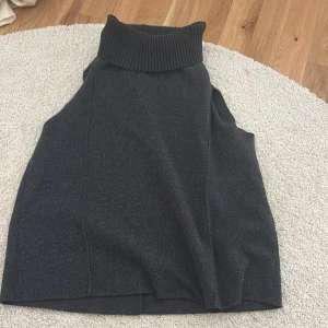 Svart ärmlös polotopp från Zara - Säljer en svart ärmlös polotopp från Zara med hög ribbad krage. Perfekt att styla lager på lager eller bära som den är. Mjuk och skön kvalitet, passar till många olika outfits.