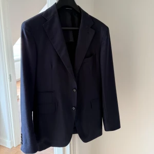 Mörkblå kostym från Tagliatore - Säljer en stilren mörkblå kostym från Tagliatore. Kavajen har klassisk passform med två knappar, spetsiga slag och flera fickor. Byxorna är raka med pressveck. Kostymen köpt förra sommaren för att användas på bal middag. Ny pris 14000kr. Pris kan diskuteras vid snabb affär   