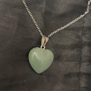 Grönt hjärta glas halsband silver imitation  - Sött halsband med en berlock av ett grönt glashjärta. Kedjan är i silverimitation och justerbar 40-45 cm. 