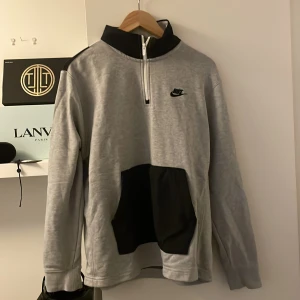 Nike half zip - Säljer en grå half zip från Nike med stor svart Nike text på ryggen  - knappt använd och är i bra skick - storlek M - passar perfekt till sommaren och hösten - hör gärna av er för frågor, pris ej hugget i sten, billigare vid snabbaffär!