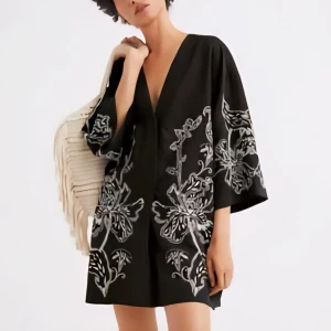 Svart kortklänning med broderade blommor - Svart kortklänning med v-ringning och vida trekvartsärmar frå än H&M. Klänningen har stora, ljusa blombroderier framtill och på ärmarna som ger en unik och cool look. Perfekt för dig som gillar statement-plagg med snygga detaljer.