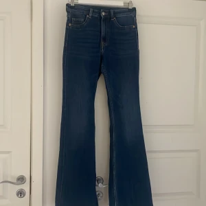 Blåa bootcut jeans - Snygga blå jeans med bootcut jeans. Klassisk femficksdesign och i ett mjukt denimtyg som sitter skönt. Perfekta för dig som vill ha en retrovibe och markerad siluett. Passar till sneakers eller boots. Kan användas till tygrester eller sy om till low waist