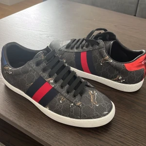 Gucci ace skor - Hej säljer ett par svarta Gucci ace skor perfekt inför den kommande sommaren. Dom är använda cirka 3-4 gånger. Säljs pga dom är lite för stora. Dom passar storlek 40,5-42. Det som medföljer är skorna, dustbag och boxen. Vid eventuella funderingar hör av er😊