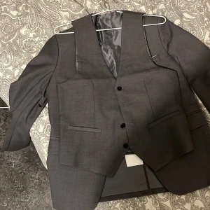 Grå kostym med väst och kavaj - En grå kostym från anomi modehus. Den är i storleken small då det var det dem valde att lägga ut den på men den var alltför liten för mig som är 183. Skulle nog säga att den är i storleken 40 på kavajen och 30 på brallorna priset får ju att diskuteras men tycker 1500 vore okej. Dels är den aldrig använd
