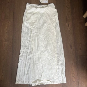Vit långkjol från Aware, storlek L - Säljer en snygg vit långkjol från Aware i storlek L. Kjolen är i linne och omlott