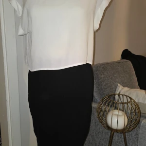 Svartvit klänning från H&M - Säljer en stilren svartvit klänning från H&M i storlek 36. Klänningen har en vit överdel med volangdetaljer på ärmarna och en svart kjoldel. Perfekt för dig som gillar enkel och klassisk stil.