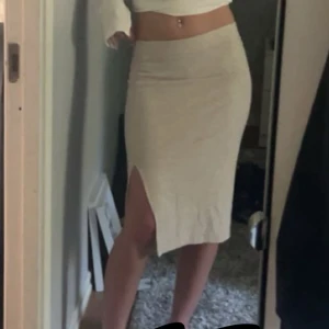 Beige ribbad kjol med slits - Säljer en beige ribbad kjol med hög midja och snygg slits framtill. Kjolen är figurnära och har en mjuk, stretchig känsla som passar perfekt till många olika stilar.