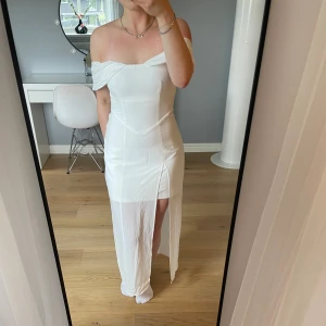 Vit offshoulder långklänning från Roomfoo - Säljer en elegant vit långklänning med offshoulder-design och slits framtill. Klänningen har figurnära passform och är perfekt till exempelvis studenten, skolavslutning, midsommar och liknande. Klänningen är köpt i Malaysia, är aldrig använd och har lappen kvar.🌼😇