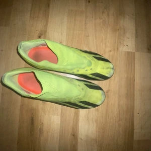 Gula fotbollsskor från Adidas - Säljer ett par gula fotbollsskor från Adidas med svarta ränder på sidorna. Skorna har låg profil och är tillverkade i syntetmaterial. Perfekta för dig som vill sticka ut på planen.