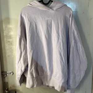 Mjukis sett  - Säljer en oversized ljuslila hoodie från Reebok med broderad logga på bröstet. Tröjan har långa ärmar, huva och breda muddar vid ärmslut och nederkant. Perfekt för en avslappnad stil. Till den ingår även ett par mjukis byxor o samma färg. Tröjan är i xs och byxorna i m.
