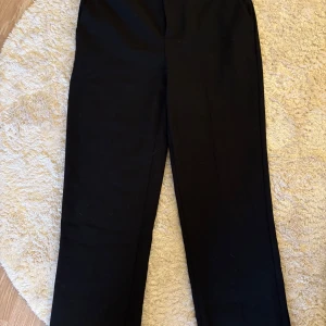 Svarta kostymbyxor från Gina Tricot - Svarta kostymbyxor från Gina Tricot med rak passform och hällor för bälte. Använd endast en gång 