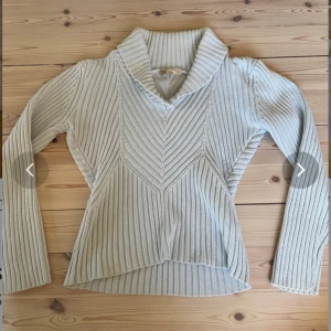 Ljusblå stickad tröja med krage från Flash Basic - Säljer en ljusblå stickad tröja från Flash Basic i storlek S. Tröjan har en bred, vikt krage och ett snyggt ribbat mönster som går i olika riktningar. Perfekt för lager-på-lager och passar till många olika stilar.