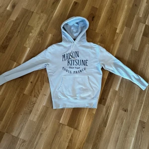  hoodie från Maison Kitsuné - Säljer en ljusblå hoodie från Maison Kitsuné. Riktigt stilren i snygg nu till sommaren 