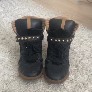 Svarta isabel marant liknade skor från Zara - Svarta sneakers från Zara med bruna detaljer och gummisula. Skorna har snörning, kardborreband med guldfärgade nitar och vadderad krage för extra komfort. Snygg och edgy stil som sticker ut. Isabel marant liknade