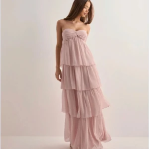 Ljusrosa bal/sommarklänning - Klänningen har en lätt och luftig känsla, perfekt för speciella tillfällen. Söt detalj med rynk framtill vid bysten. Knytet går att ljusters och använda som en sjal eller som att koppla samman med klänningen och ha runt halsen. (Enbart använd 1 gång)