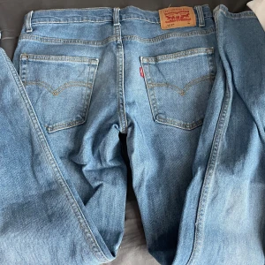 Levi's straight blå jeans - Säljer ett par klassiska blå Levi's  jeans med  raka ben. Jeansen har fem fickor, dragkedja och knapp i midjan samt Levi's ikoniska läderpatch bak. Perfekta till vardags och passar till det mest. Bra färg för sommaren. Passar mellan 175-180 skulle jag säga. 29-32 