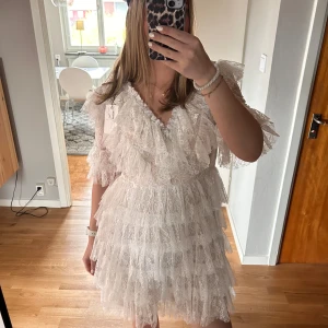 Vit spetsklänning med volanger från By Malina - Supersöt vit kortklänning från By Malina med flera lager volanger och v-ringning. Perfekt till tex student/ midsommar. Säljer pga köpte förra året och den kommer ej till användning längre! Är en tjej som brukar ha s/m och denna sitter bra på mig💕