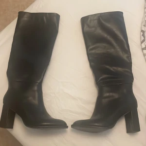 Svarta höga stövlar med klack - Säljer ett par svarta höga stövlar som jag köpte i London från Office. De har en  bred klack och rund tå. Skorna är i skinn (inte riktig skinn)  och har en stilren design som passar perfekt till höst och vinter, går även att styla till sommaren också.  Snygga att styla till både kjol och jeans. Inga defekter. Pris  kan diskuteras vid snabb affär💘