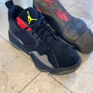 Svarta Nike Air Jordans med röda och gula detaljer - Säljer ett par svarta Nike Air Jordans med snygga röda och gula detaljer. Skorna har snörning, rund tå och platt sula. Perfekta för dig som vill ha en sportig och stilren look. Ikonisk Jumpman-logga på plösen och cool design baktill. Kan gå ner i pris vid snabb affär.