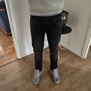 Jack & Jones jeans - Säljer ett par svarta Slimfit jeans från Jack & Jones med snyggt tvättad look. Jeansen har klassisk femficksdesign, normal midja och smal passform hela vägen ner. Materialet är stretchigt för extra komfort och de har diskreta detaljer vid fickorna.
