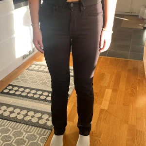 Levi's Premium 724 High Rise Straight - Svarta Levi's Premium 724 High Rise Straight jeans med hög midja och raka ben. Snygg och klassisk modell i stretchigt jeanstyg som sitter riktigt bra. Perfekta till sneakers eller boots och funkar året runt.