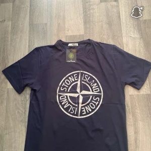 Mörkblå Stone Island t-shirt XXL men passar mer på XL - Snygg mörkblå t-shirt från Stone Island i storlek XXL. Stor logga framtill i vitt med klassisk kompassdesign. T-shirten är i mjuk bomull och har en normal passform med korta ärmar. Perfekt för dig som gillar streetwear och vill sticka ut.