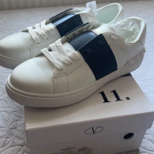 Valentino Garavani Open sneakers vit/blå - Snygga Valentino Garavani Open sneakers i vitt skinn med bred marinblå rem över mitten.