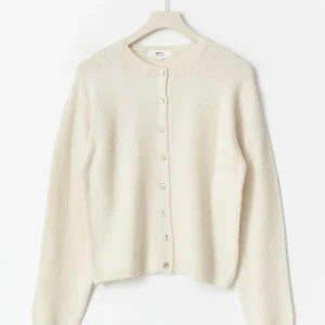 Vit kofta från Gina Tricot, storlek S - Jag säljer en mjuk och stilren vit kofta från Gina Tricot i storlek S! Koftan har rund halsringning, långa ärmar och knäppning framtill med små vita knappar. Perfekt att slänga på sig över en topp för en enkel och clean look☺️