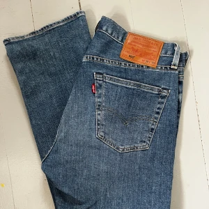Levi's 501 blå jeans straight fit - Klassiska blå Levi's 501 jeans med rak passform och normal midja. Jeansen har fem fickor, knappgylf och den ikoniska läderpatchen bak. Tillverkade i slitstarkt bomullsjeans, perfekt för en avslappnad och tidlös look.