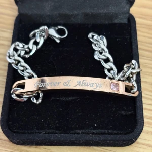 Armband i silver och roséguld - Snyggt armband med grov silverlänk och en platta i roséguld med texten 'Forever & Always' ingraverad. Plattan har en liten rosa sten som detalj. Perfekt som present till någon speciell eller för att ge din stil lite extra känsla.