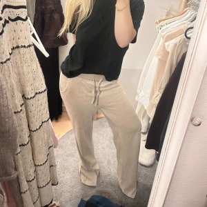Beiga mjukisbyxor med snörning - Säljer ett par beiga mjukisbyxor i mjukt material med bred resår och snörning i midjan. Byxorna har raka, lite vidare ben och sidofickor. Perfekta för chill dagar eller när du vill vara extra bekväm.