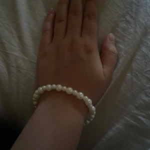 Pärlarmband med vita pärlor - Snyggt armband med vita pärlor i klassisk rund form. Perfekt för dig som gillar stilrena accessoarer med lite extra elegans. Pärlorna är jämnt placerade runt hela armbandet och ger en fräsch och tidlös vibe.