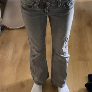 Grå jeans från Gina Tricot - Snygga grå jeans från Gina Tricot i storlek 146. Modellen har klassisk femficksdesign med knappdetalj på bakfickan, jeansen är tillverkade i mjukt denimtyg och har låg midja med bootcut. 