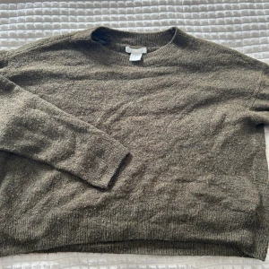 Grön stickad tröja från H&M - Mysig grön stickad tröja från H&M i storlek XS. Tröjan har en klassisk rund halsringning och långa ärmar. Perfekt för lager-på-lager och chill höst- och vinterstil. Materialet känns mjukt och ger en avslappnad vibe.