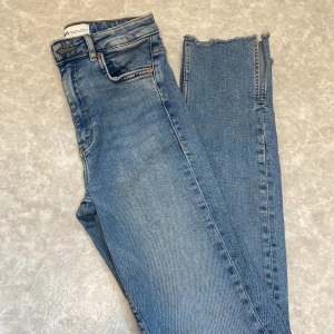 Blå croppade jeans från Zara - Snygga ljusblå jeans från Zara i modell med hög midja och croppade ben med rå, fransig kant. Klassisk femficksdesign och dragkedja med knapp. Perfekta för en avslappnad och trendig look.