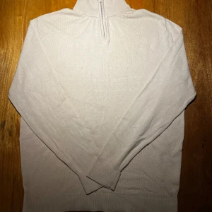 Beige stickad half zip tröja - Snygg beige stickad tröja med half zip och hög krage. Tröjan har långärmad passform och ribbade muddar vid ärmslut och nederkant. Perfekt för lager-på-lager och chill stil under höst och vinter. Har ingen tag men passar herrstorlek S och har även mycket stretch. Vid funderingar är det bara att kontakta mig jag är ärlig och rak med svar.