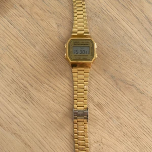 Guldig digital klocka från Casio - Säljer en klassisk digital klocka från Casio i guldigt rostfritt stål. Klockan har fyrkantig display, länkarmband och flera funktioner som alarm, datum och belysning. Perfekt accessoar för dig som gillar retrostil. Mottagaren står för frakten💕