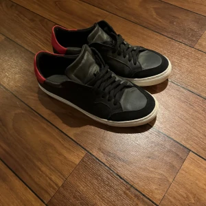 Svarta arigato - Snygga svarta arigato med vit sula och röd detalj på hälen.