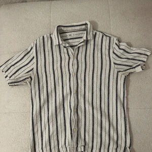 Randig kortärmad skjorta från Zara - Snygg kortärmad skjorta från Zara i vitt med marinblåa rände!