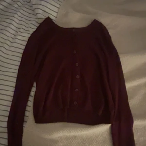 Mörkröd kofta med knappar - Snygg mörkröd kofta med långa ärmar och knappar hela vägen framtill. Perfekt att slänga över en t-shirt eller klänning för en chill och stilren look. Mjuk och skön, passar till många outfits.