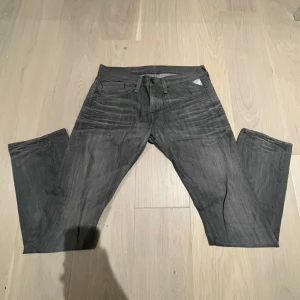 Replay grå jeans med raka ben - Snygga grå jeans från Replay med raka ben och klassisk femficksdesign. Jeansen har metallmärke på fickan och Replay-logga på bakfickan. Perfekt för dig som gillar stilrena och snygga jeans. W32 L32